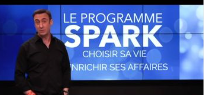 Franck Nicolas devant un écran géant où il y a écrit le nom de sa formation "SPARK"